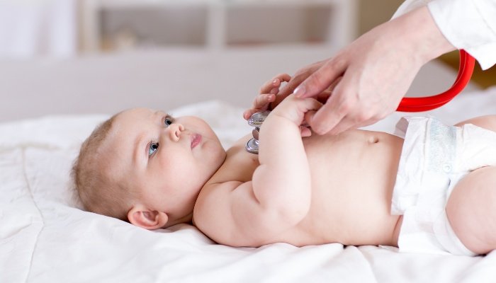 A doctor using a stethoscope to listen to a baby's heart.
