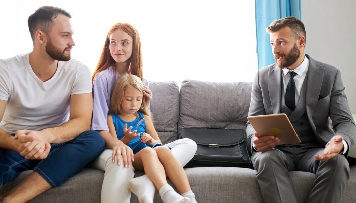 Parents with a little girl seated on a couch speaking to a divorce lawyer.