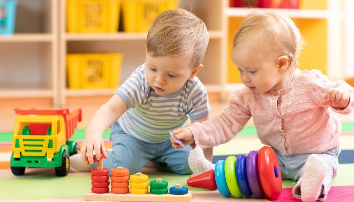 Two toddlers playing together on the floor at a daycare center.
