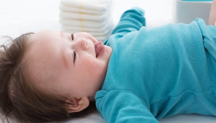 A cute baby laughing at his mother during a diaper change.
