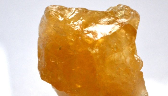 A rough citrine crystal on a gray background.
