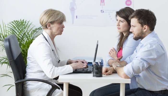 A couple speaking with a fertility specialist at doctor's office.
