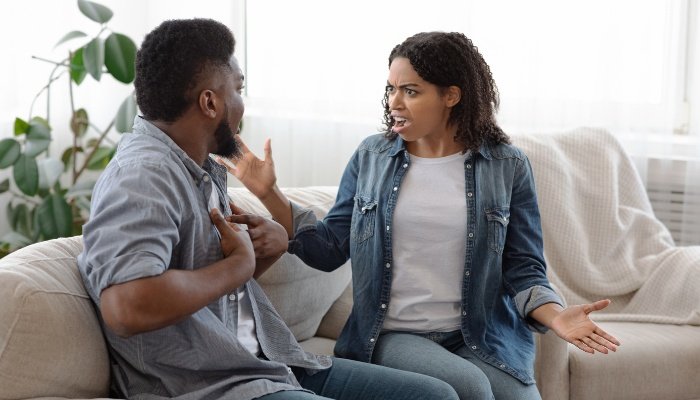 A couple sitting on the couch having a heated argument.