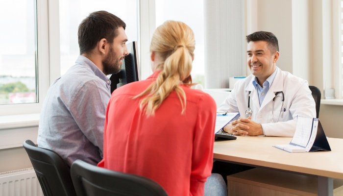 A couple speaking with their fertility doctor in his office.