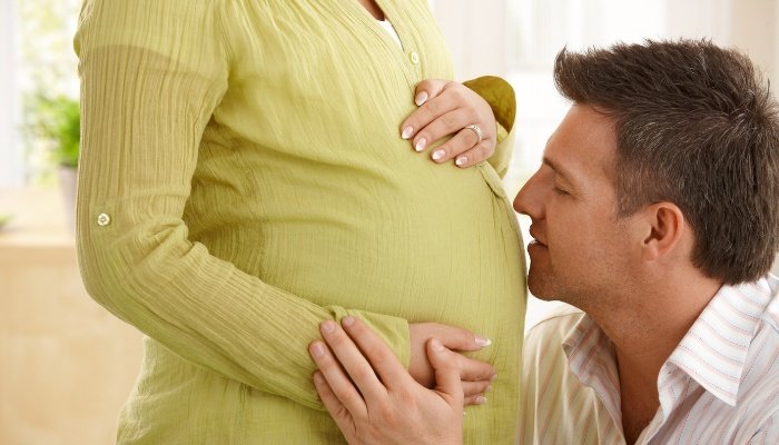 An expectant father talks to his wife's pregnant belly.