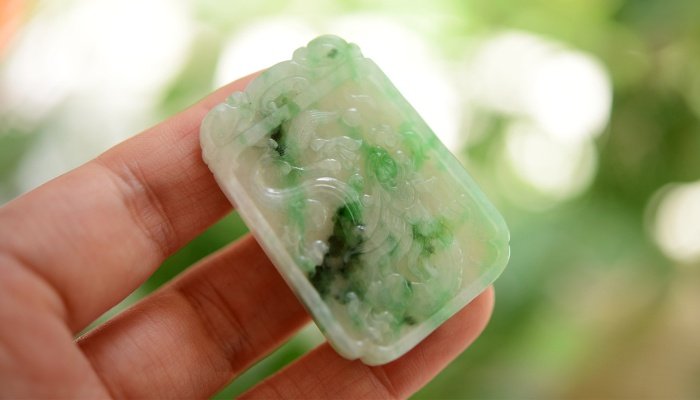 A jade gemstone held in a woman's hand.