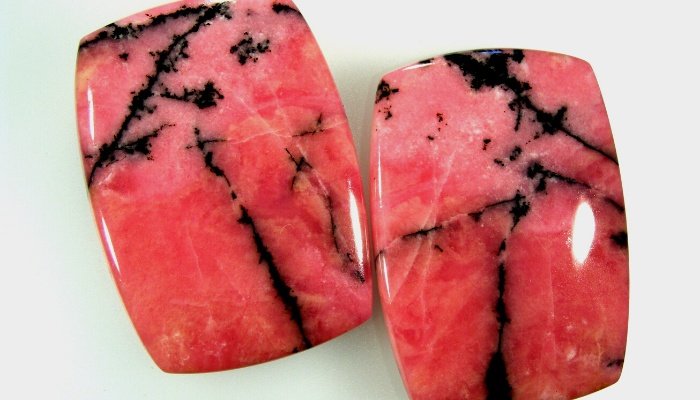 Two rhodonite gemstones on white.