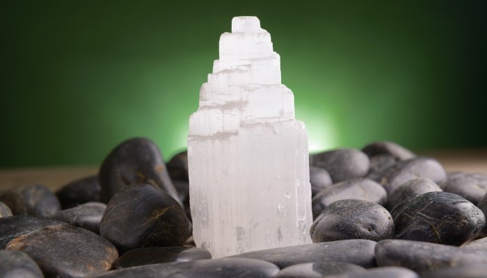 A selenite crystal on a bed of smooth rocks.