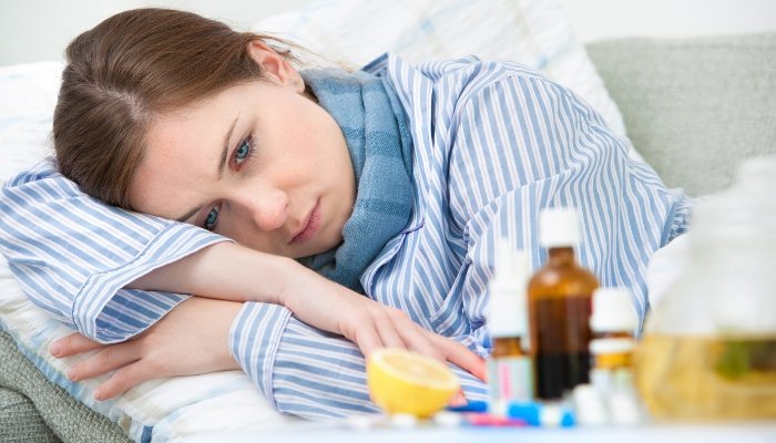 A sick woman lying in bed with medications on the nightstand.