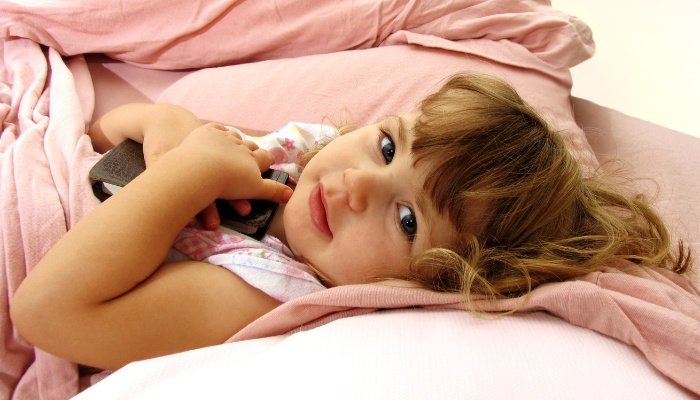 An adorable little girl lying in her toddler bed with guard rails.