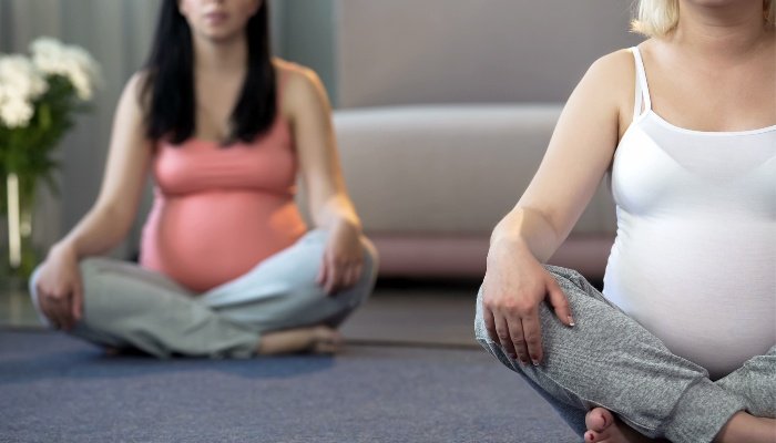 Two ladies sitting on the floor during a childbirth class.