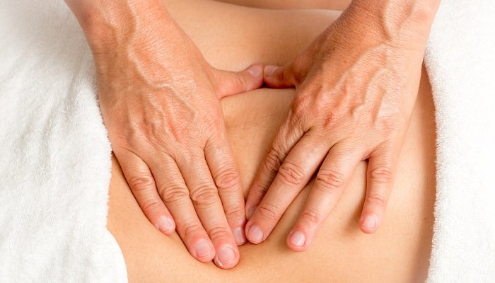 A woman receiving a fertility massage on her abdomen.