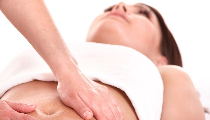 A woman is having her abdomen massaged in hopes of benefiting fertility.