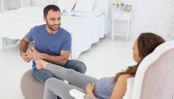 A husband gently massages and rubs his pregnant wife's feet.