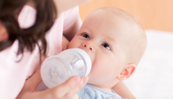 A mother feeding her infant a bottle of milk.