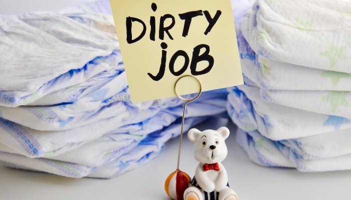 Two stacks of diapers with a sign in front reading Dirty Job.