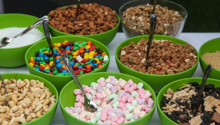An assortment of sweet toppings for ice cream displayed buffet style for a party.