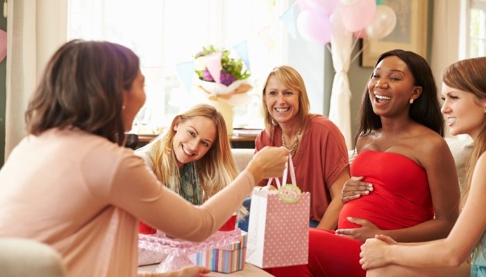 A group of woman enjoying gift-giving at a baby shower.