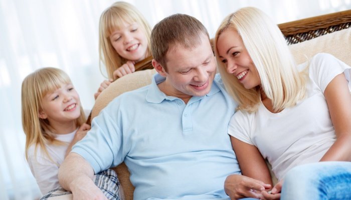 A husband and wife enjoying a special memory while twin girls watch and eavesdrop over their shoulders.