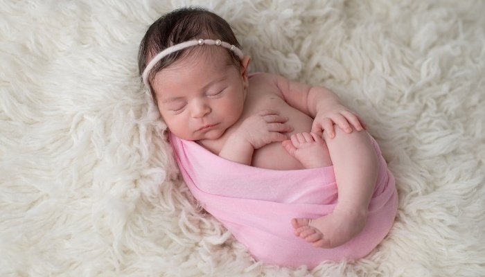 A newborn baby girl posed for photos as if hatching from an egg.