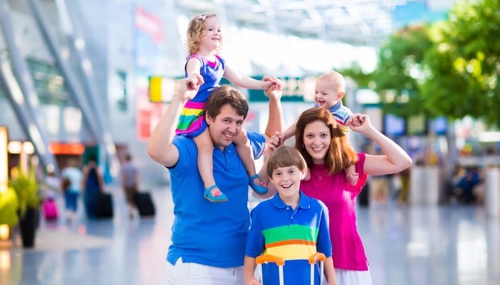 A family with two young children and an older child inside an airport.