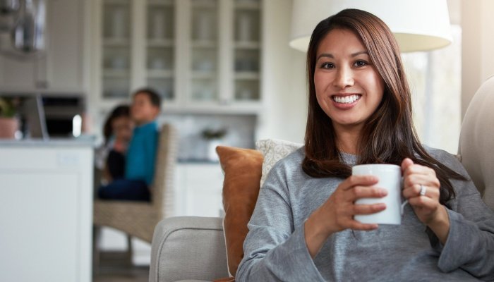 A mom taking some me time on the couch with a cup of coffee.
