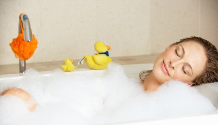 A woman relaxing in a bubble bath with lots of bubbles.