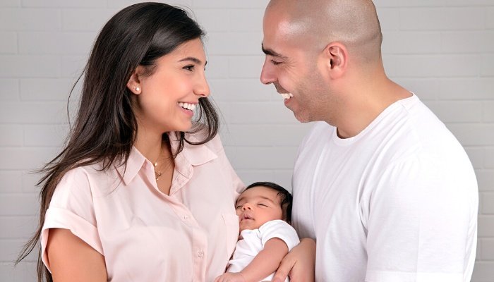 Happy parents holding their newborn son between them.