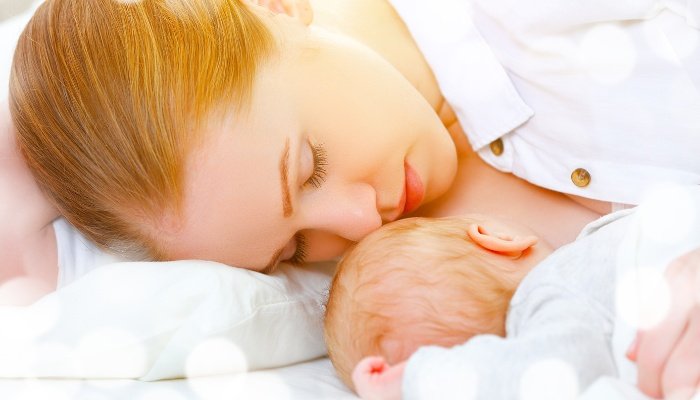 A new mom lying beside her newborn to nurse and rest.