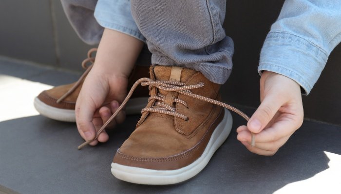 A close-up look at a little boy tying his shoe.