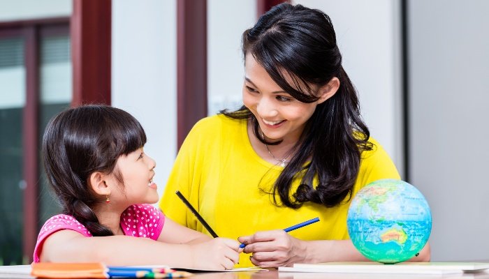 A mother teaching her daughter geography at their kitchen table.